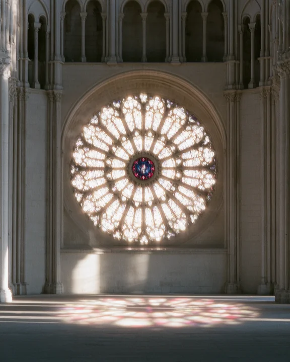 Gothic cathedral rose window seen from inside, with radial stone tracery and deep blue and ruby stained glass
